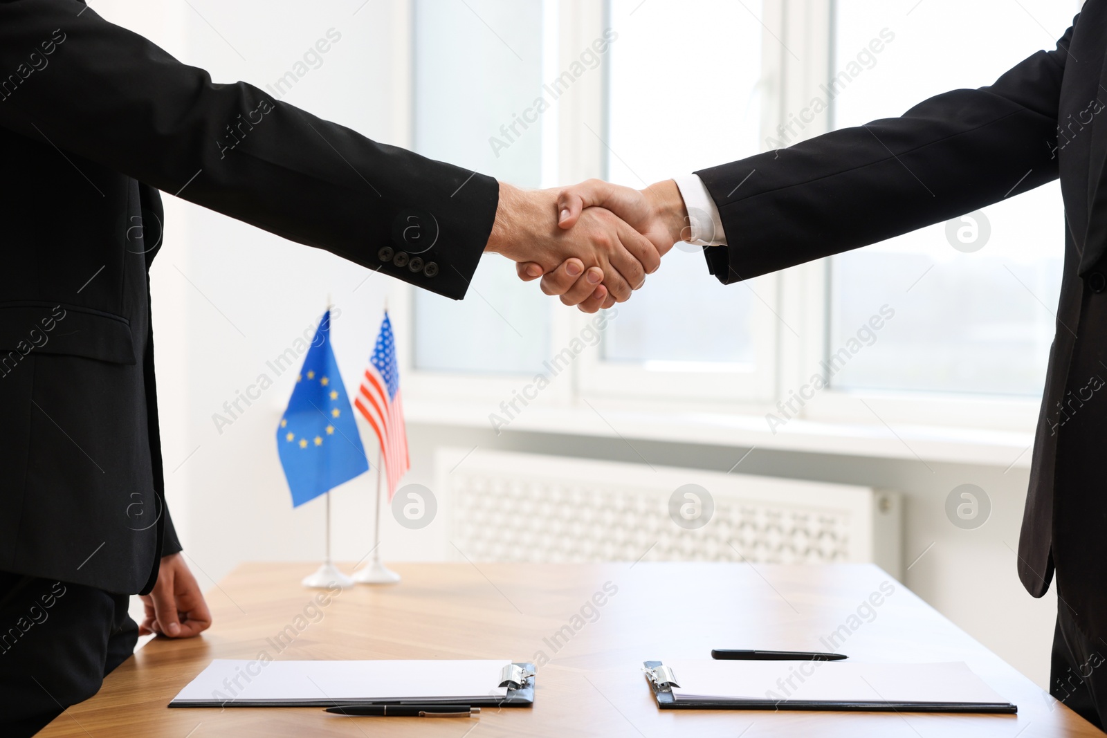 Photo of Diplomats shaking hands during meeting indoors, closeup