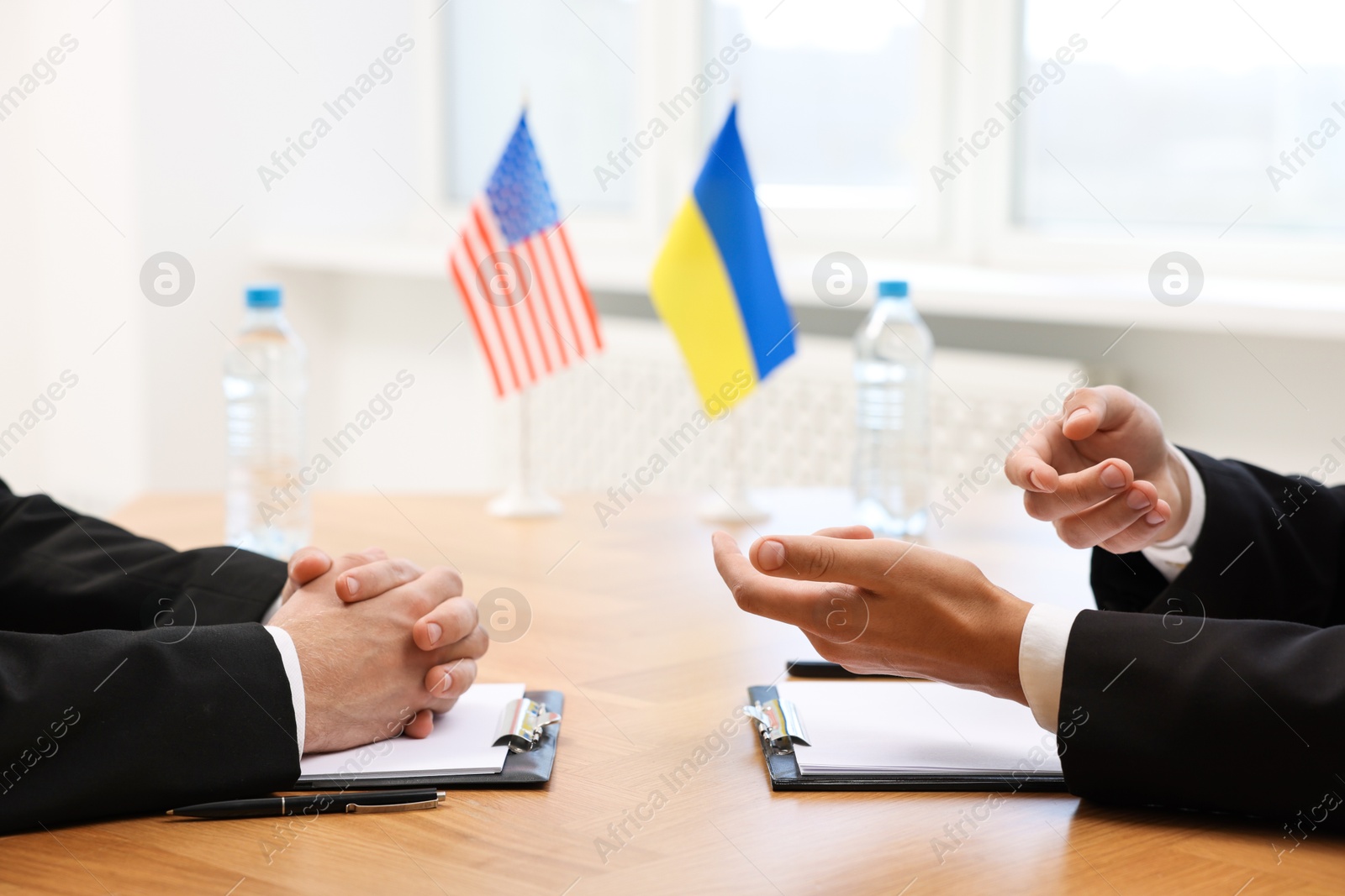 Photo of Diplomats negotiating during meeting at wooden table indoors, closeup