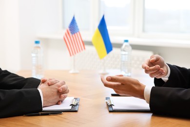 Photo of Diplomats negotiating during meeting at wooden table indoors, closeup