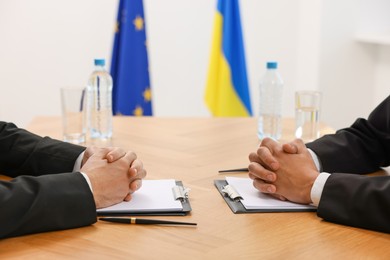 Diplomats negotiating during meeting at wooden table indoors, closeup