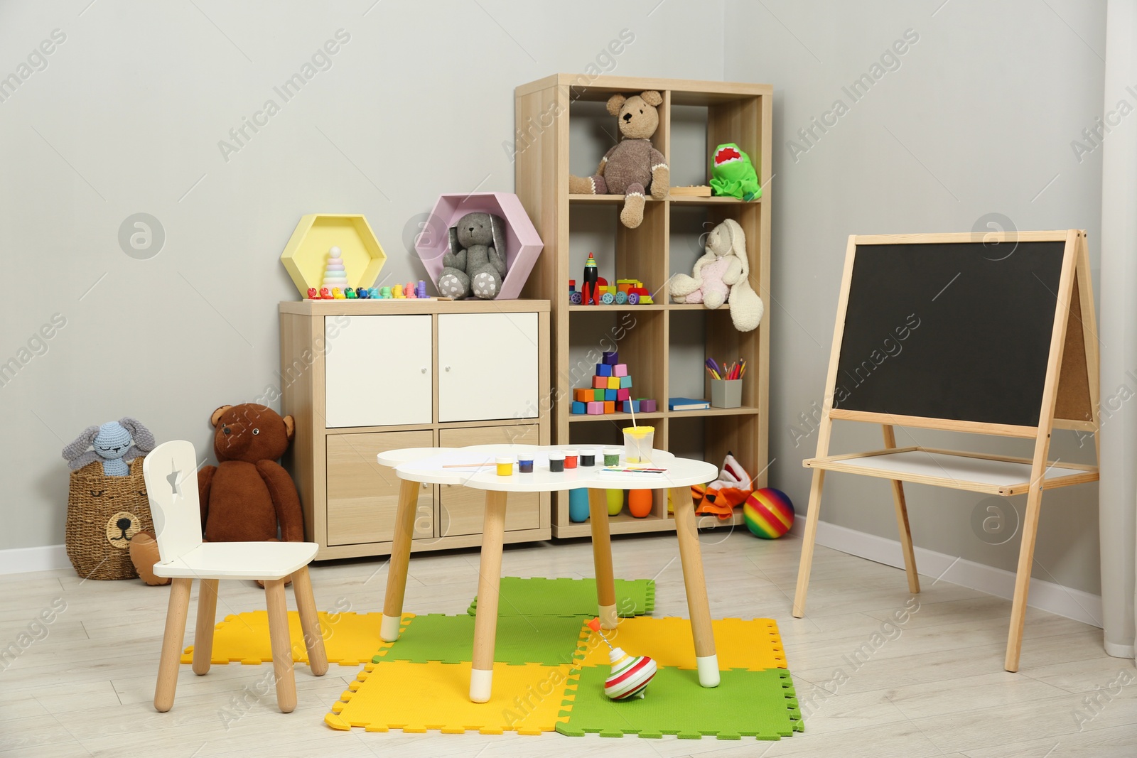 Photo of Beautiful kid's room interior with toys, paints and stylish furniture