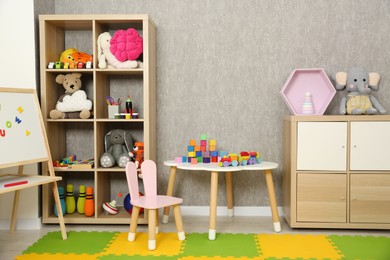 Photo of Beautiful kid's room interior with toys, whiteboard and stylish furniture