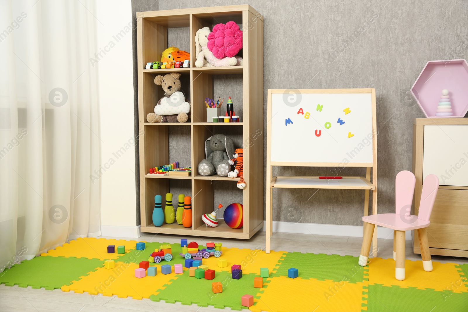 Photo of Beautiful kid's room interior with toys, whiteboard and stylish furniture