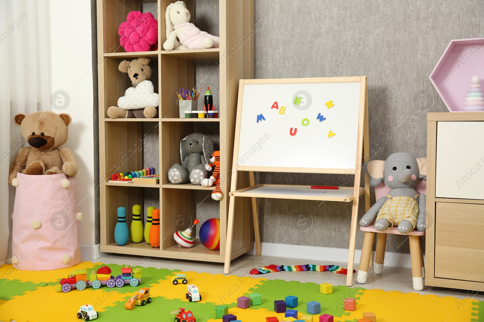 Photo of Beautiful kid's room interior with toys, whiteboard and stylish furniture