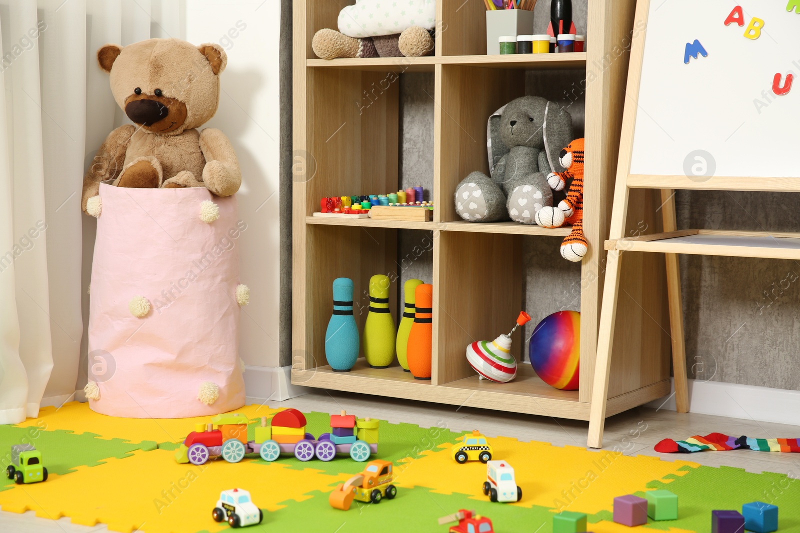 Photo of Beautiful kid's room interior with toys, whiteboard and stylish furniture