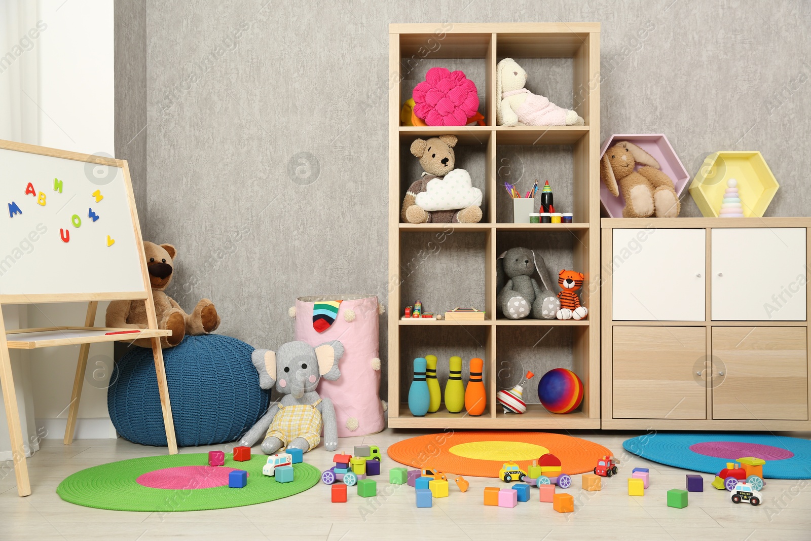 Photo of Beautiful kid's room interior with toys, whiteboard and stylish furniture