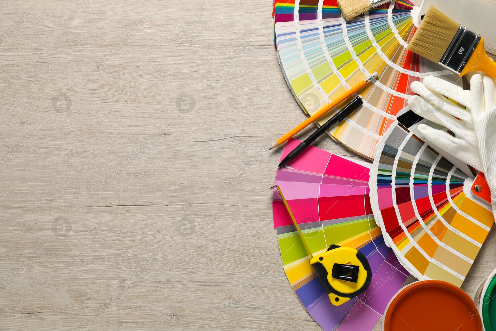 Photo of Different painter's tools on wooden table, flat lay with space for text. Decorating and design