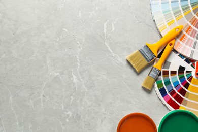 Photo of Different painter's tools on grey marble table, flat lay with space for text. Decorating and design