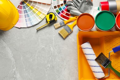 Photo of Different painter's tools on grey marble table, flat lay with space for text. Decorating and design