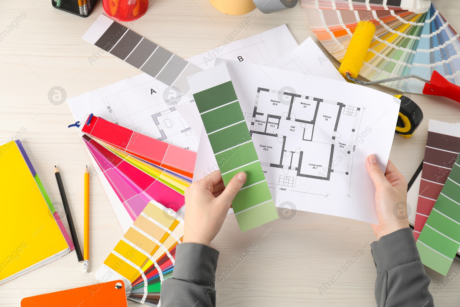 Photo of Designer with color selection chart working on house project at table, closeup