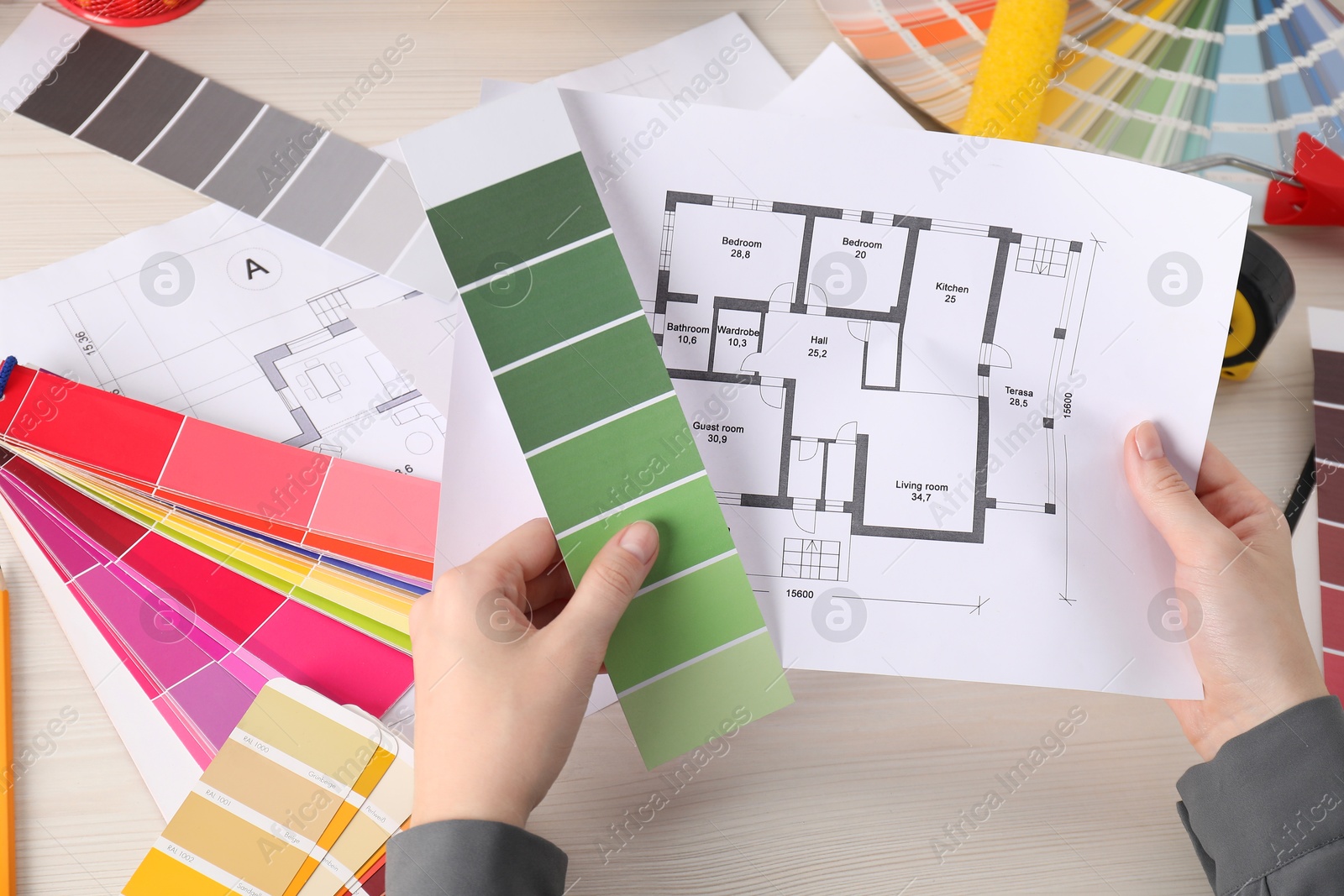 Photo of Designer with color selection chart working on house project at table, closeup