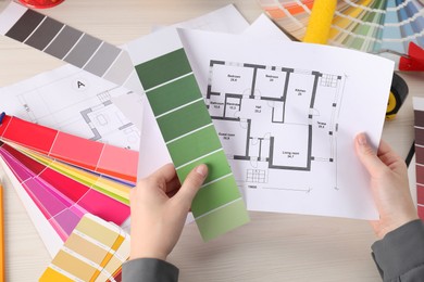 Photo of Designer with color selection chart working on house project at table, closeup