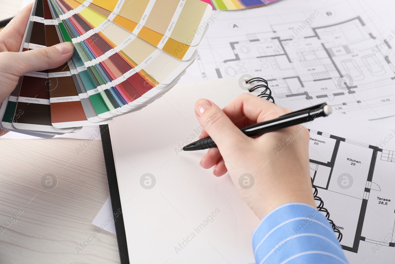 Photo of Designer with color selection chart working on house project at table, closeup