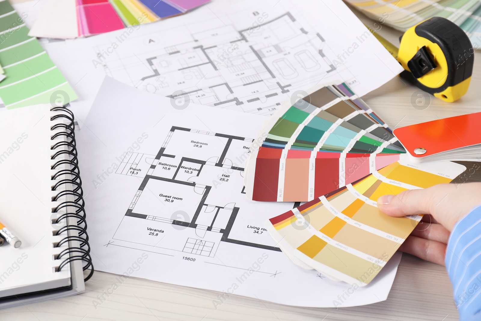 Photo of Designer with color selection chart working on house project at table, closeup