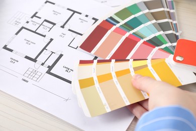 Photo of Designer with color selection chart working on house project at table, closeup