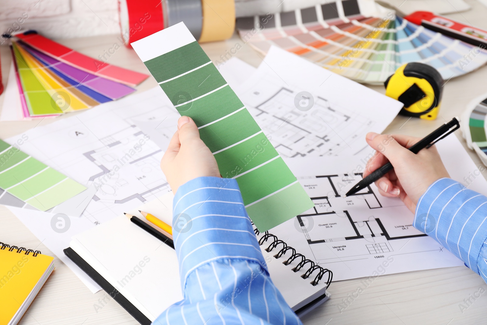 Photo of Designer with color selection chart working on house project at table, closeup