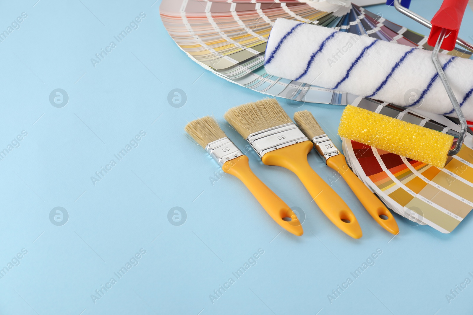 Photo of Different painter's tools on light blue table, space for text. Decorating and design