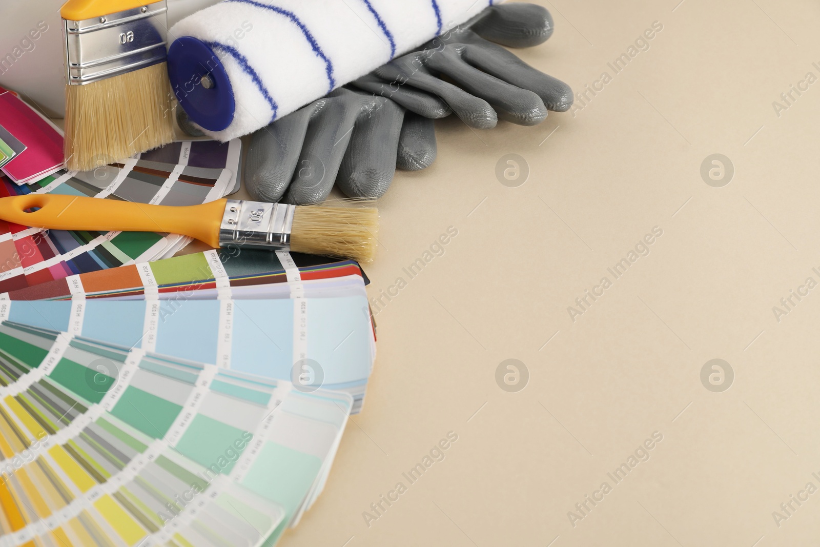 Photo of Different painter's tools on beige table, space for text. Decorating and design