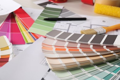 Photo of Color selection charts, house plans and other tools on table, closeup. Decorating and design