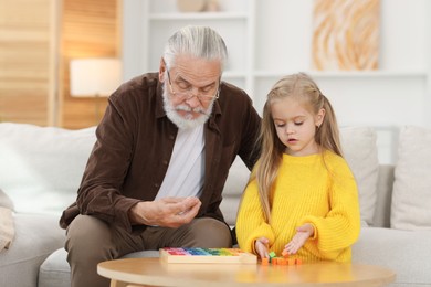 Grandpa and his granddaughter playing with math game Times table tray at home