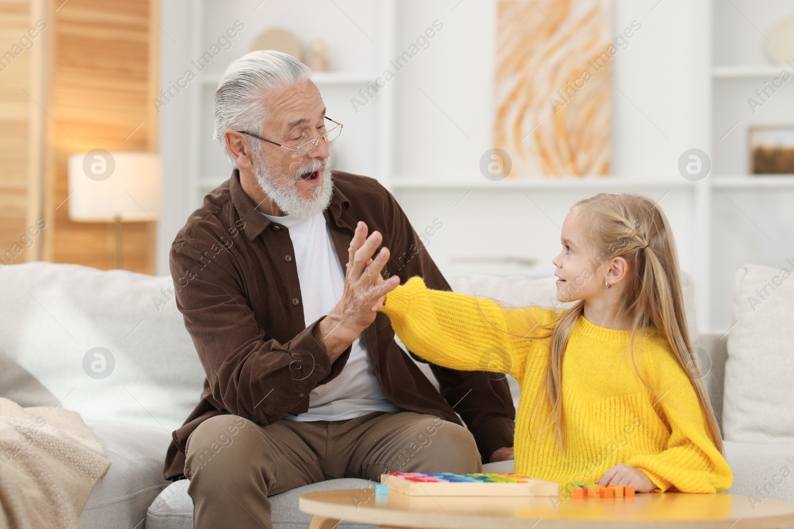 Photo of Grandpa and his granddaughter playing with math game Times table tray at home