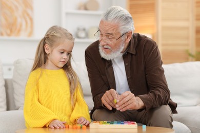 Photo of Grandpa and his granddaughter playing with math game Times table tray at home