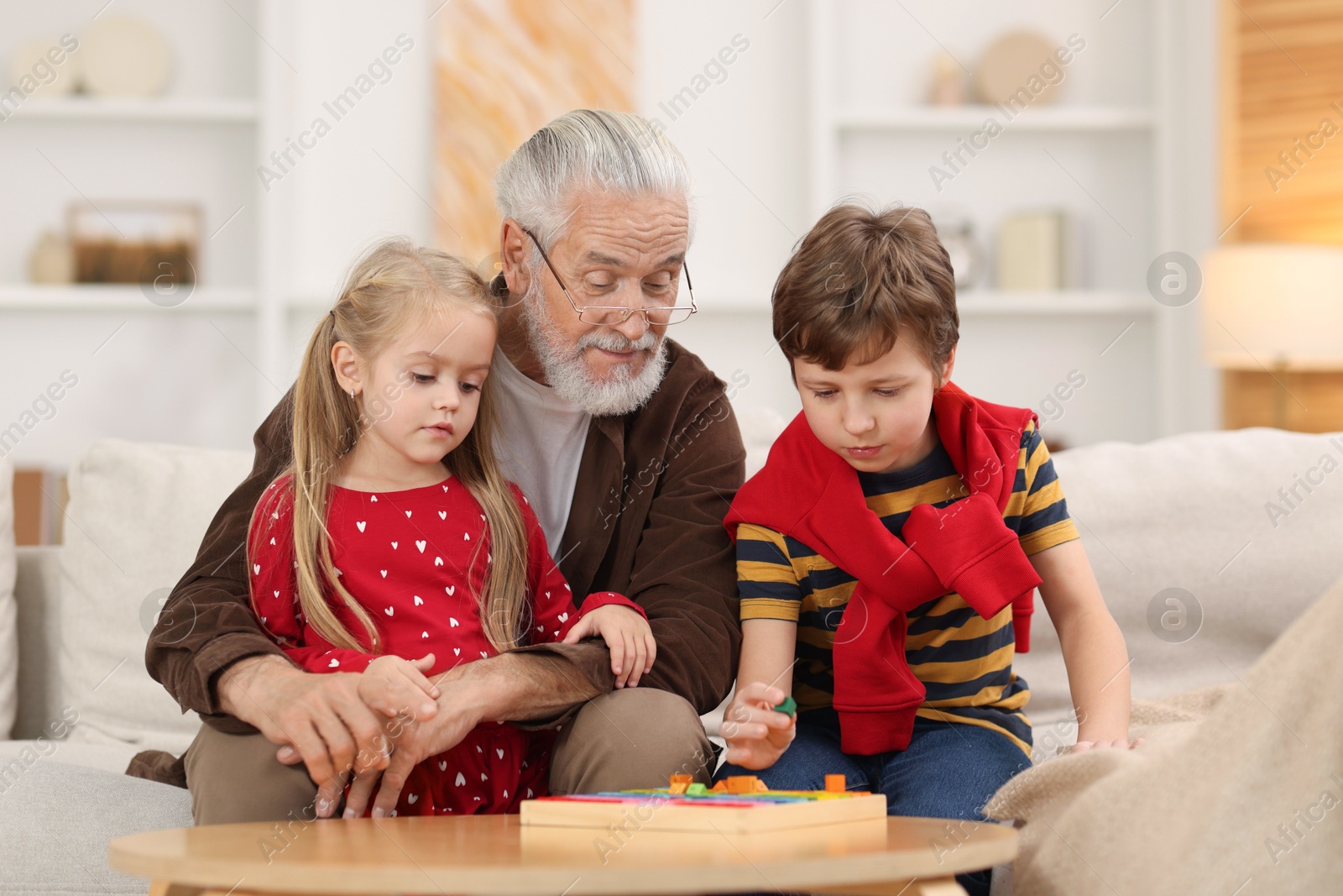 Photo of Grandpa and his grandkids playing with math game Times table tray at home