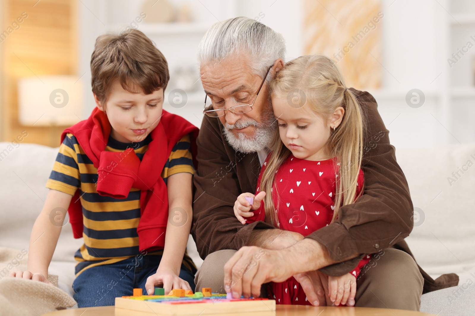 Photo of Grandpa and his grandkids playing with math game Times table tray at home