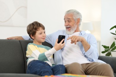 Photo of Grandpa and his grandson watching something on smartphone at home