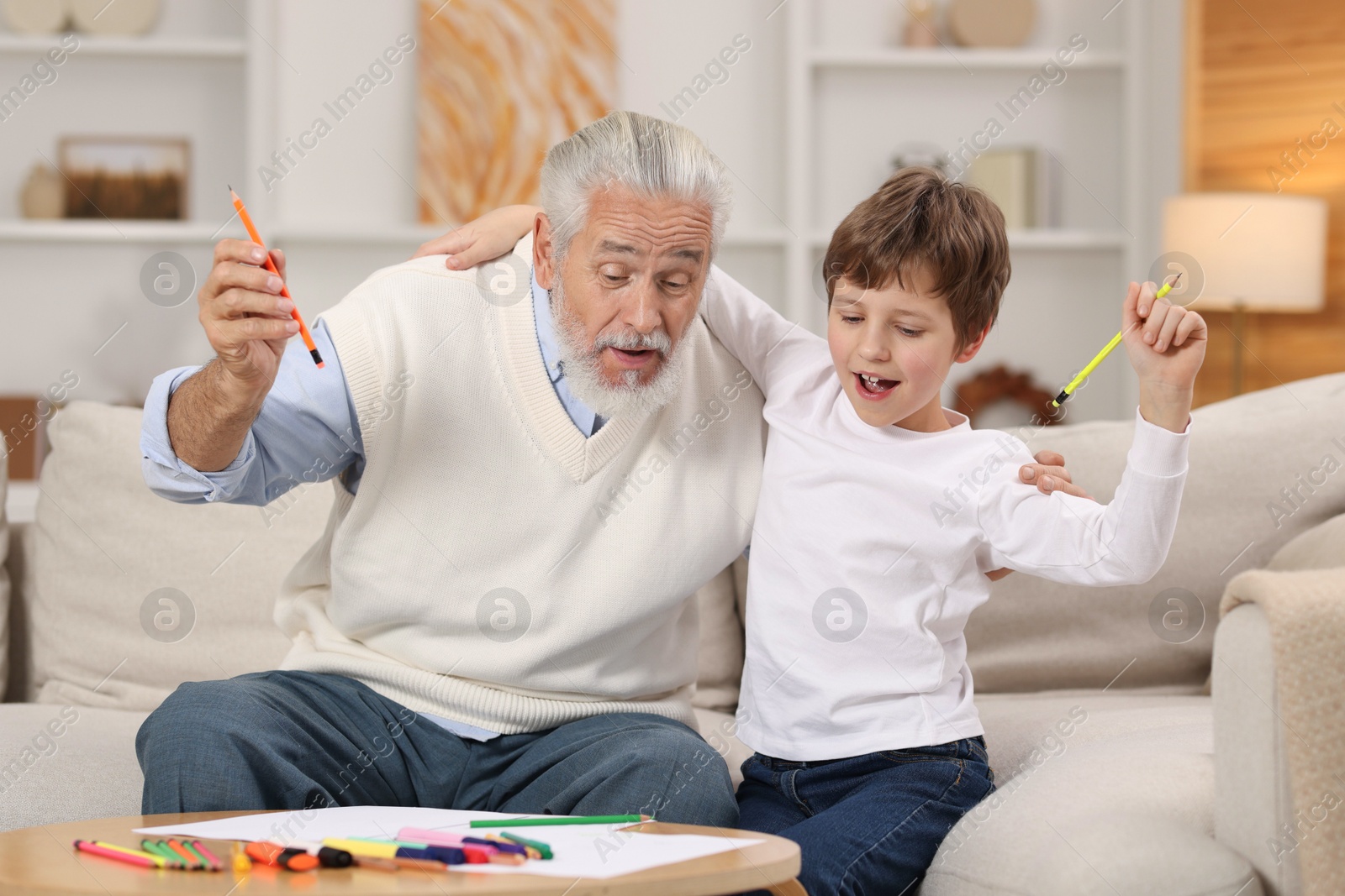 Photo of Grandpa and his grandson drawing at table indoors