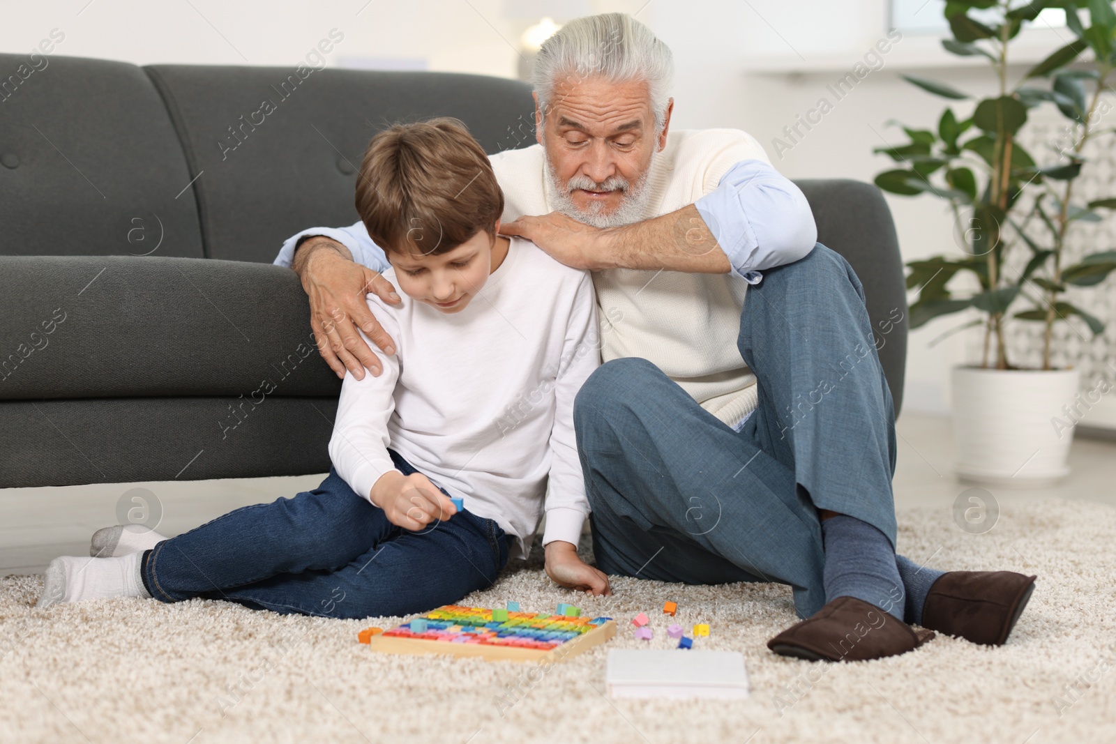 Photo of Grandpa and his grandson playing with math game Times table tray on floor at home