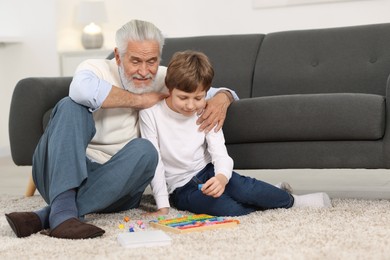 Photo of Grandpa and his grandson playing with math game Times table tray on floor at home