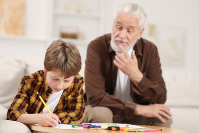 Photo of Grandpa and his grandson drawing at table indoors