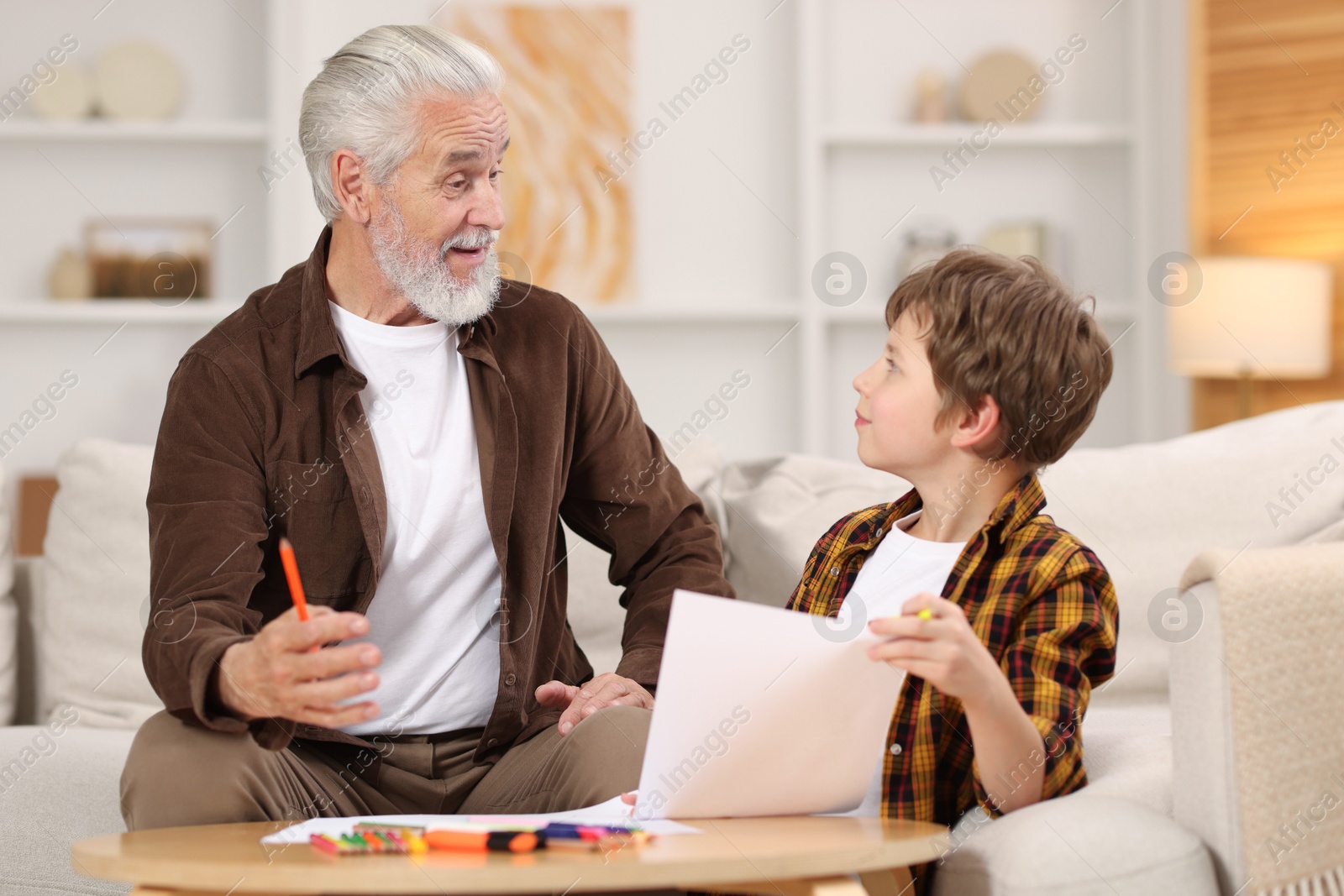 Photo of Grandpa and his grandson drawing at table indoors