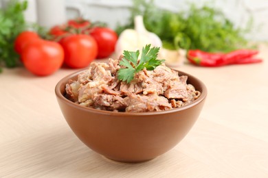 Photo of Canned meat with parsley in bowl on wooden table, closeup