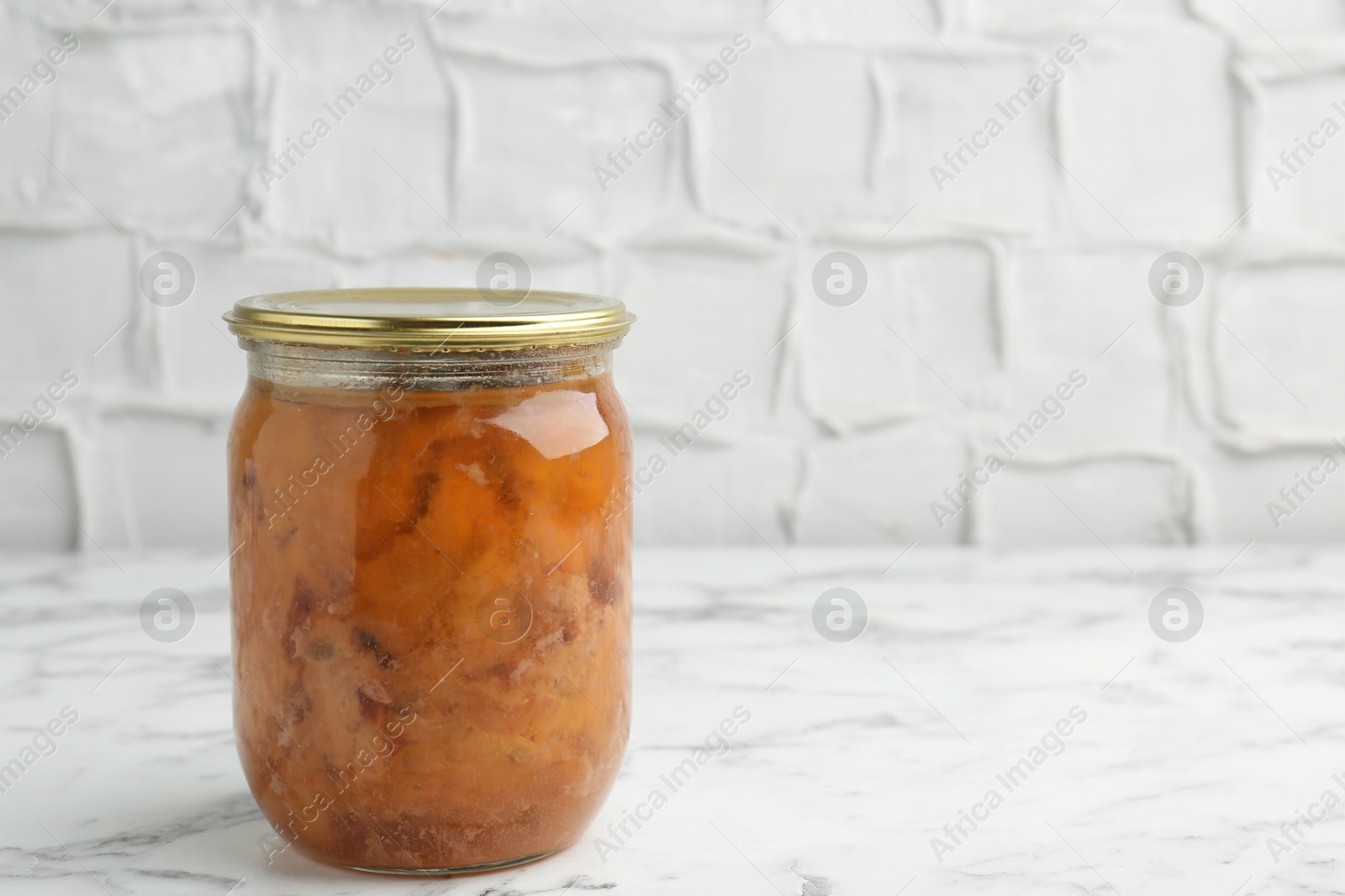 Photo of Canned meat in glass jar on white marble table, space for text