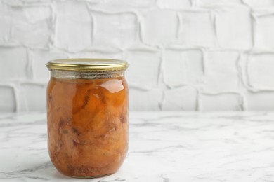 Photo of Canned meat in glass jar on white marble table, space for text