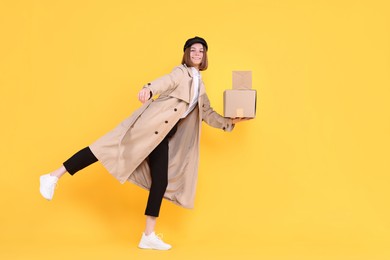 Photo of Happy postwoman with parcels on yellow background