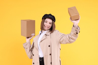 Photo of Happy postwoman with parcels on yellow background