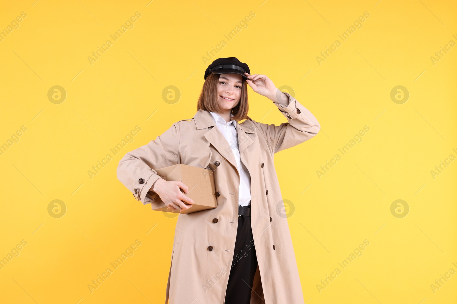 Photo of Happy postwoman with parcel on yellow background