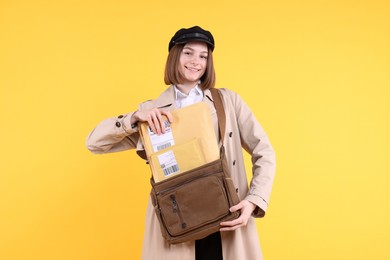 Photo of Happy postwoman with bag and envelopes on yellow background