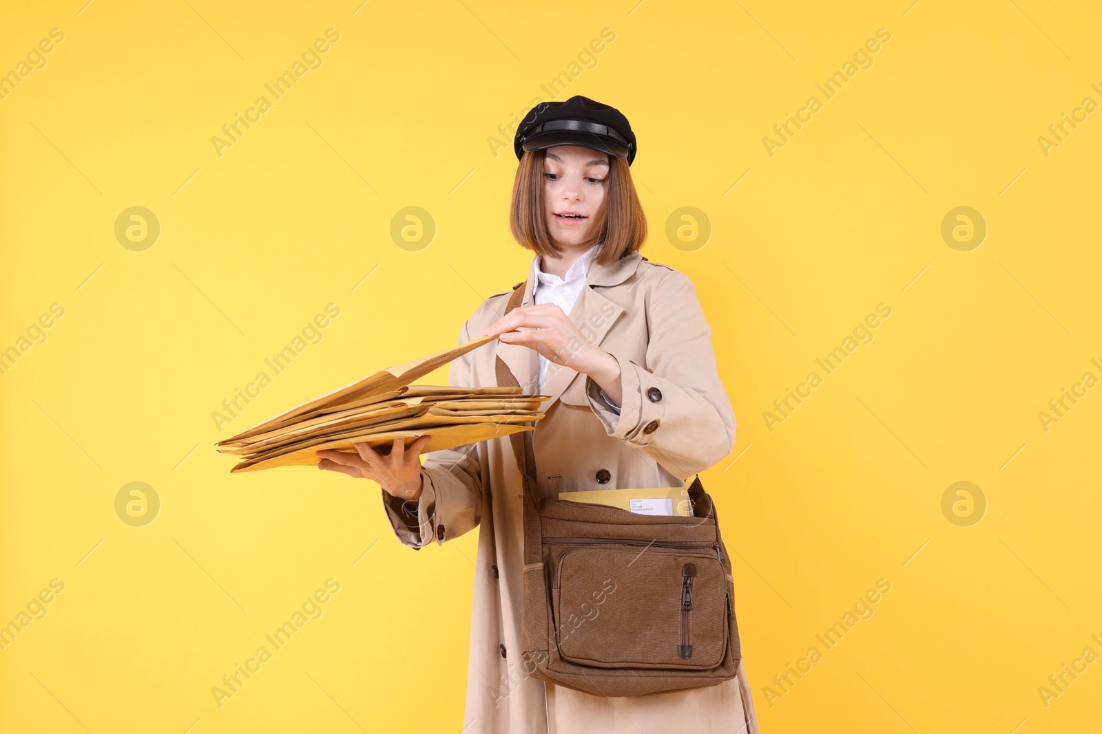 Photo of Postwoman with bag and envelopes on yellow background