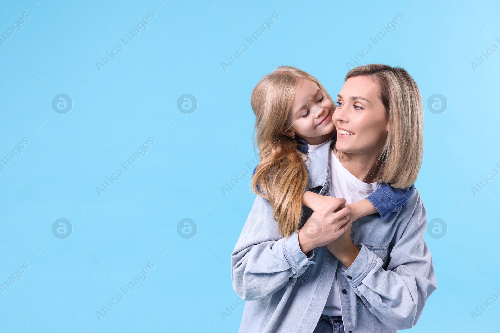 Photo of Cute little girl hugging her mom on light blue background, space for text. Happy Mother's Day