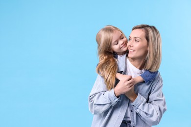 Photo of Cute little girl hugging her mom on light blue background, space for text. Happy Mother's Day