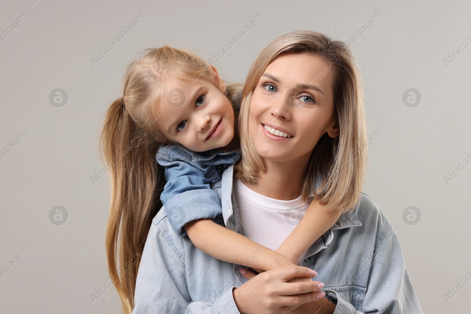 Photo of Cute little girl with her mom on gray background. Happy Mother's Day