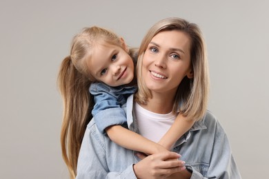 Cute little girl with her mom on gray background. Happy Mother's Day