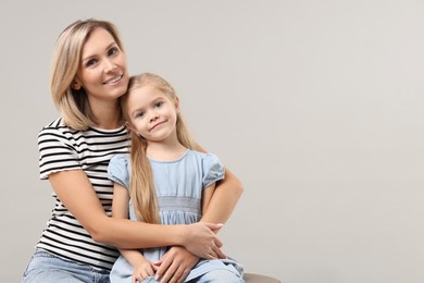 Cute little girl with her mom on gray background, space for text. Happy Mother's Day