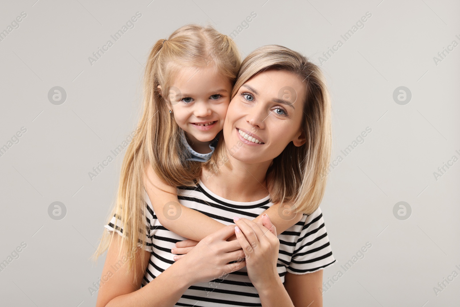 Photo of Cute little girl with her mom on gray background. Happy Mother's Day