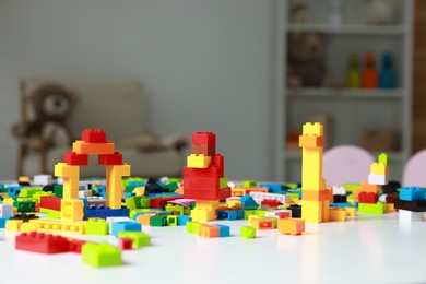 Photo of Construction toy. Figures made with building bricks and colorful blocks on white table indoors