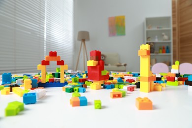 Photo of Construction toy. Figures made with building bricks and colorful blocks on white table indoors